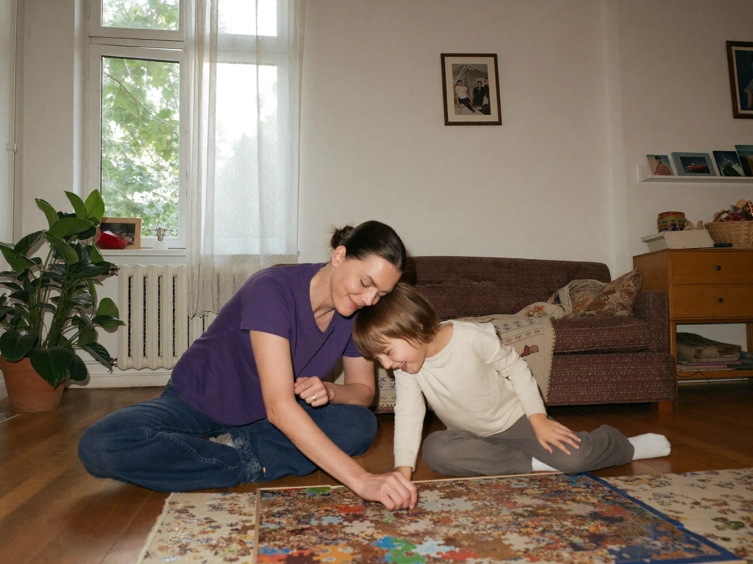 Haushaltshilfe und Kind sitzen am Boden und legen ein Puzzle
